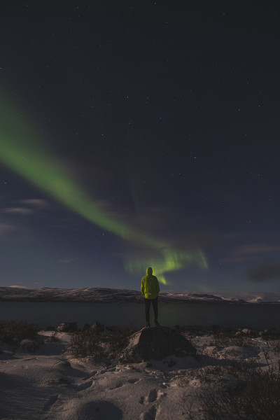 在芬兰拉普兰的Kilpisjarvi，在一个无云的夜晚，北极光扫过一个大湖。绿莹莹的北极光在天空中舞