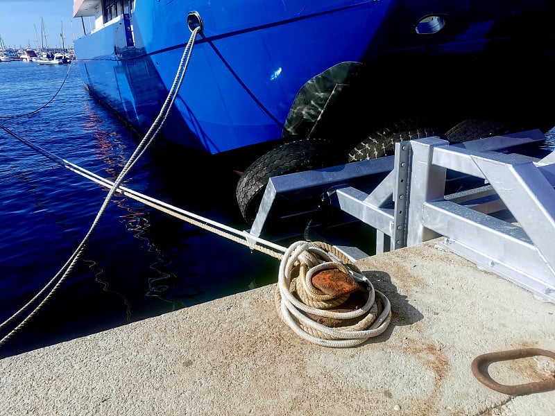 Ship mooring ropes secured around a port bollard