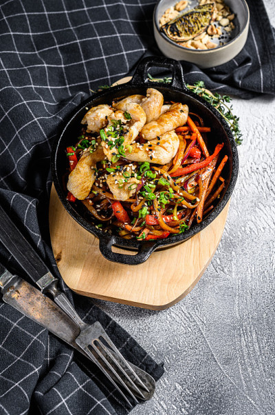 乌冬面与鸡肉和蔬菜在平底锅中煸炒。灰色的背景。俯视图