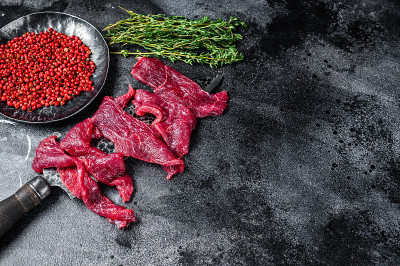 新鲜牛肉，切成细条用于炖牛肉。黑色背景。前视图。本空间