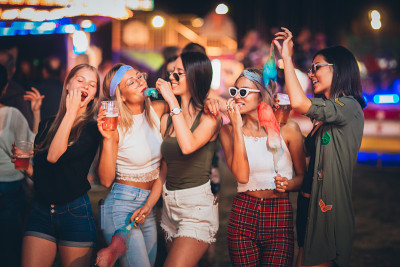 女性朋友在游乐园吃棉花糖喝啤酒