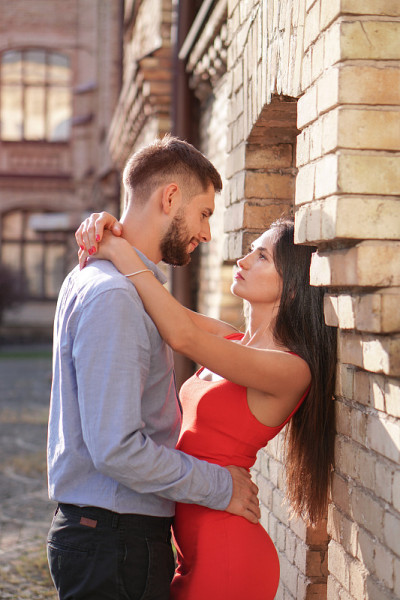 一对美丽的男人和女人在一个奇妙的建筑解决方案的背景。一个女孩和一个男孩的浪漫主题。春天，夏天照片关系
