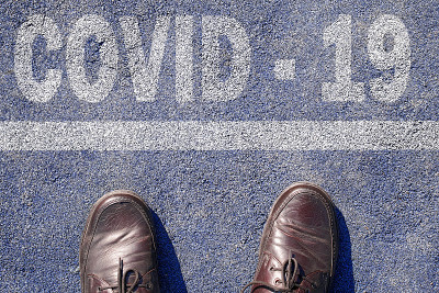 俯视图男子脚站在沥青边界线和文本COVID-19