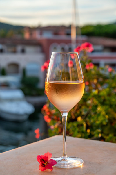 品尝当地的玫瑰葡萄酒在夏天与帆船港口格里莫德的背景，普罗旺斯，法国