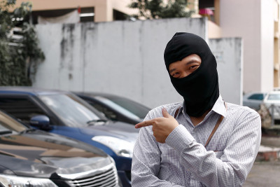 戴着黑色巴拉克拉瓦帽的蒙面小偷试图闯入汽车