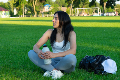 带着运动器材在足球场上休息的爱运动的女孩合适的女孩