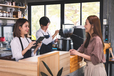 一位顾客向咖啡师点了一杯热拿铁。亚洲员工咖啡店制作热咖啡并为顾客服务。中小企业的概念。