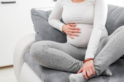 怀孕疲惫不堪的女人带着肚子、腿和疼痛的问题躺在家里的沙发上，生病了。