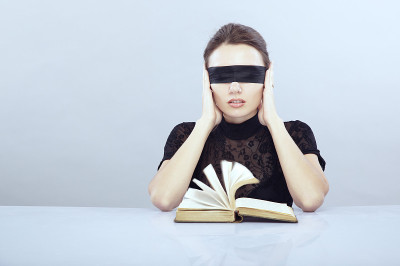 女人戴着眼罩，双手捧着头，旁边的书正在翻动书页。不可理解主题的象征