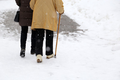 在大雪中拄着拐杖走路的女人