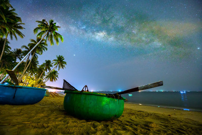 午夜景观与篮子船，椰子树剪影和银河在天空