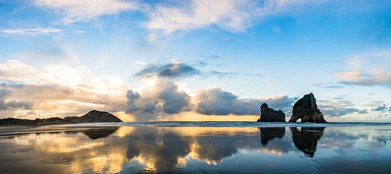 全景视图。美丽的哈瓦瑞基海滩和著名的岩石。夕阳的景象，金色的光和剪影。纳尔逊，南岛，新西兰。