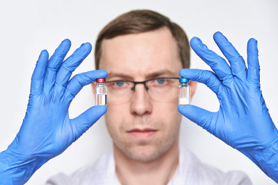 Person in gloves hold two vaccine bottles
