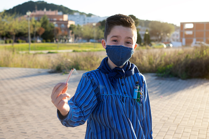 一个穿着瓦伦西亚法拉斯(Valencian Fallas)服装的孩子，展示着一根灯芯玩鞭炮