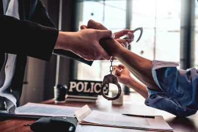戴手铐的犯罪嫌疑人在审讯室接受警察讯问，刑法概念