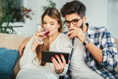 年轻夫妇在家里享用美酒，并使用数码平板电脑。