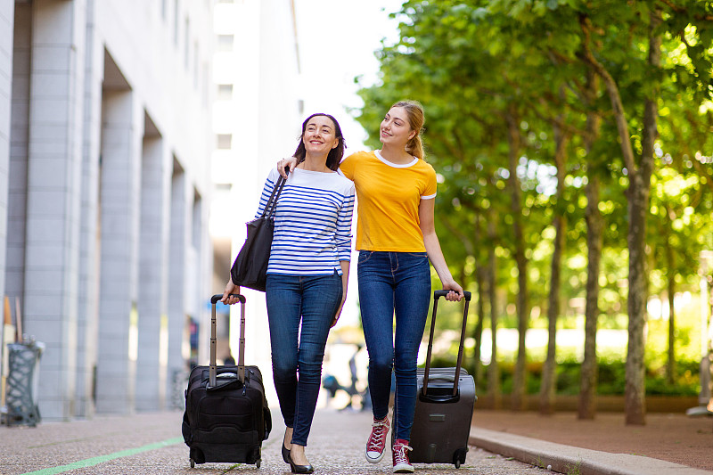全身快乐的母女带着旅行袋出门散步