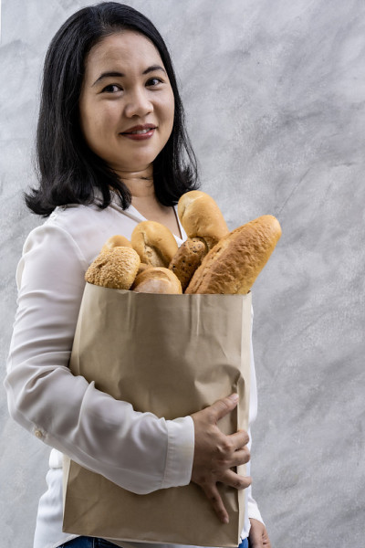 肖像亚洲家庭主妇拿着杂货店的面包袋。