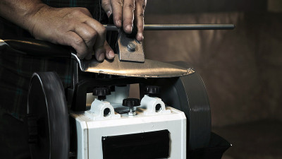 Man sharpens knives on a grinder. Close up hand