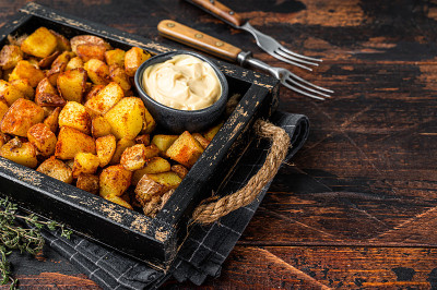 Patatas bravas是传统的西班牙土豆小吃。深色木制背景。前视图。本空间