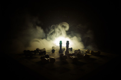 棋牌游戏的经营理念和竞争理念以及战略理念。象棋人物在烟雾缭绕的黑暗背景上。