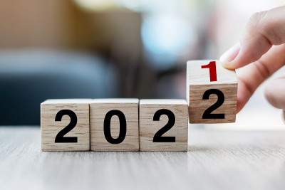 商人手持木质立方体与翻转块2021年至2022年的文本在桌子的背景。决议，策略，解决方案，目标，业务
