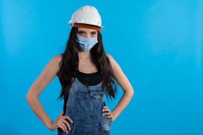 一名戴着头盔和防护面具的年轻女子在建筑工地等待上级的命令。