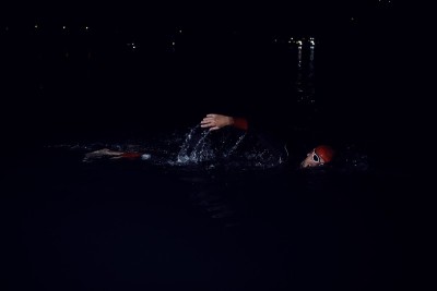 铁人三项运动员穿着潜水服在黑夜里游泳