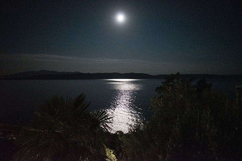 夜海，月亮在天空中闪耀，倒映在海面上