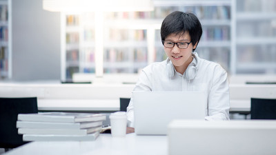 亚洲人大学学生在图书馆使用笔记本电脑
