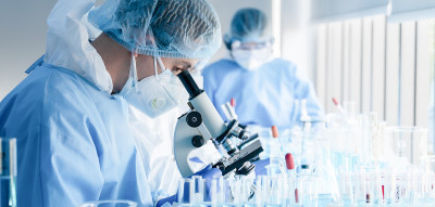 生物化学研究科学家团队在制药研究实验室使用显微镜进行冠状病毒疫苗开发