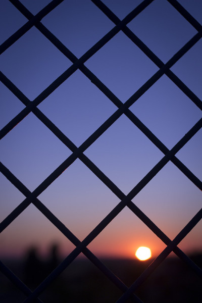 夕阳和蓝色的黄昏天空和铁丝网栅栏