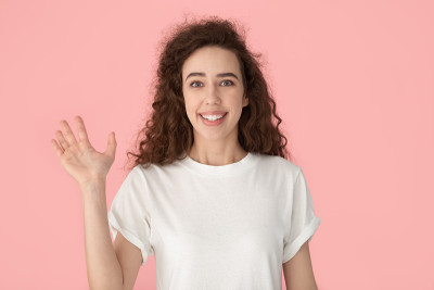 年轻的女士微笑着挥手，做着招呼的姿势。