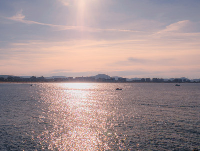 日落时分，小船在坎塔布里安海上航行，背景是拉雷多海滩
