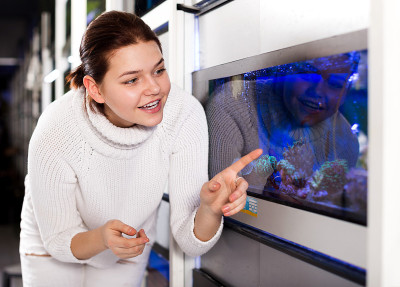 水族店的女孩指着彩色的鱼