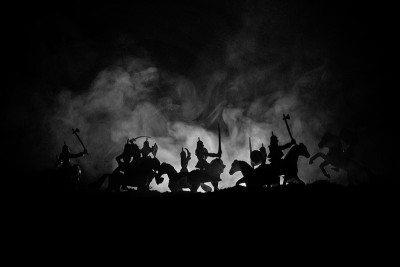 有骑兵和步兵的中世纪战斗场景。剪影的人物作为单独的对象，战斗的战士之间的黑暗色调的雾背景。夜景。