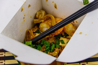 泰式炒米粉与虾和豆腐在打开的纸盒外卖。泰国菜，外卖