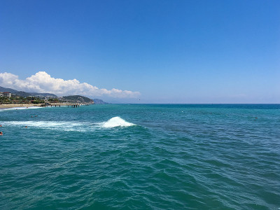 不同寻常的海景。在远处，你可以看到海岸，沐浴着人影和厚厚的云在海岸边的山后面。