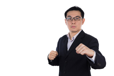 愤怒的亚洲华人穿着西装，双手紧握拳头