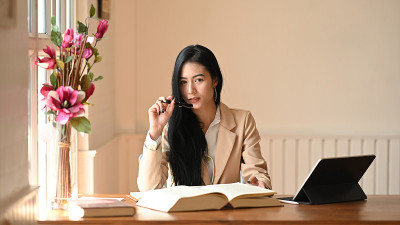 肖像女性编辑在办公室工作空间的书。