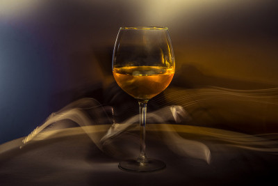 白色的葡萄酒在一个创造性的黑色背景上的桌子上的玻璃杯。在酒吧吸烟，在聚会或迪斯科舞会上喝酒。在黑暗中