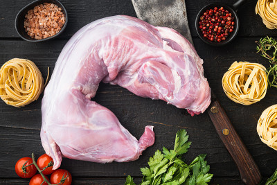 生兔肉和煮食材炖干面条，放在黑色木桌背景上，俯视图平铺