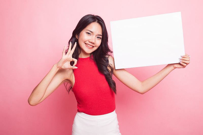 年轻的亚洲女子用白纸表示OK。