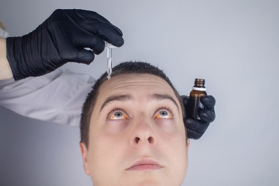 眼药水的特写。一个男人去看医生，他把药水滴进病人的眼睛里。概念治疗结膜炎、眼疲劳、青光眼。病毒或细菌