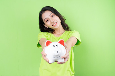 亚洲女孩手里拿着小猪存钱罐存钱的概念