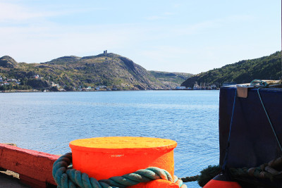 这是圣约翰港(St. john's Harbour)码头上系在系柱上的系泊缆绳的特写，眺望港口对面的