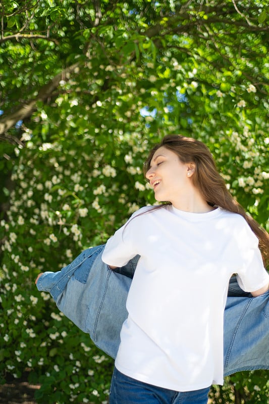 女人旋转。一个美丽的年轻女子围绕着一棵美丽的树旋转，树下开着白色的、芬芳的茉莉花。享受生活，感受自由