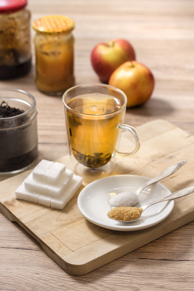 由方糖制成的金字塔。蔗糖和白色散粉放在茶匙上。用玻璃杯冲泡的绿茶放在一块木板上。