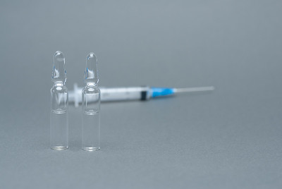 灰色背景上有两支安瓿和注射器药物的概念