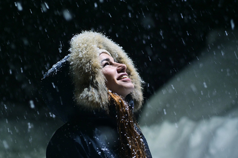 一个美丽的女孩在一个下雪的夜晚看风景的特写。